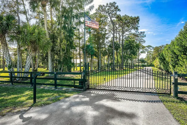 a view of a white house with a big yard and potted plants