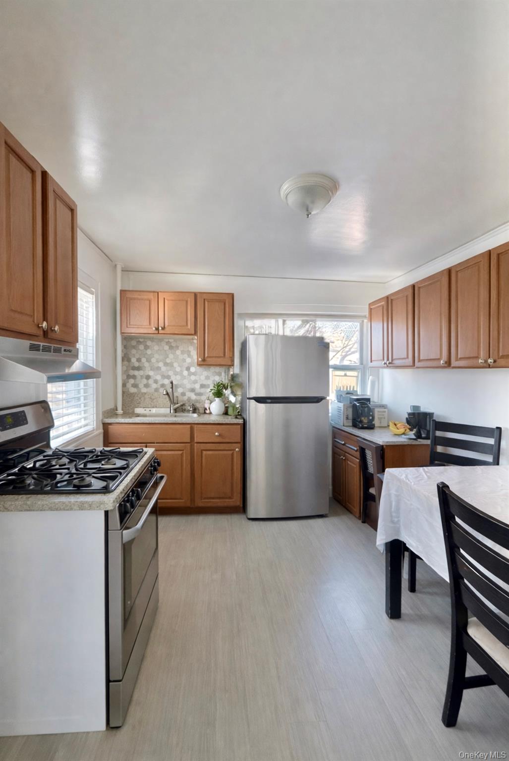 130 Clinton Avenue, Unit 2 New Rochelle, NY 10801 - Photo 2 of 6 Kitchen with stainless steel appliances, light countertops, under cabinet range hood, brown cabinetry, and healthy amount of natural light