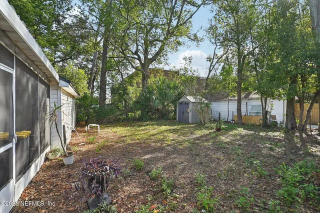 a backyard of a house with a large tree and wooden fence