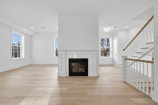 a view of an empty room with fireplace and wooden floor