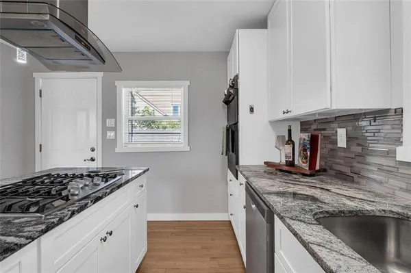 a kitchen with granite countertop stainless steel appliances sink stove and cabinets