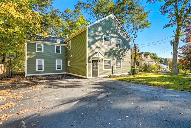 a view of a house with a yard and large tree