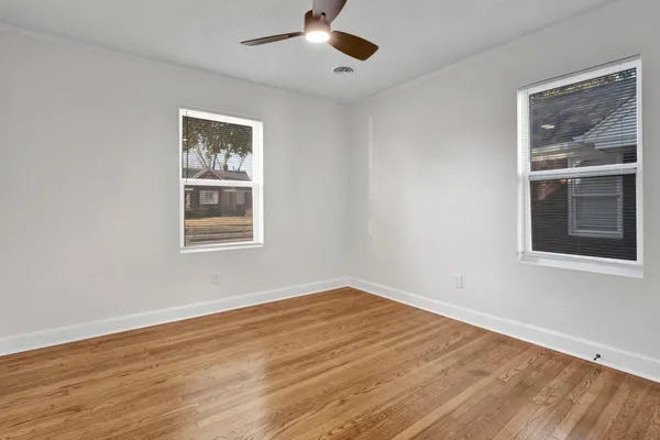 a view of empty room with wooden floor and fan