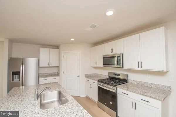 a kitchen with granite countertop a stove sink and refrigerator