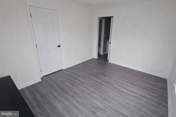 a view of an empty room with wooden floor and closet