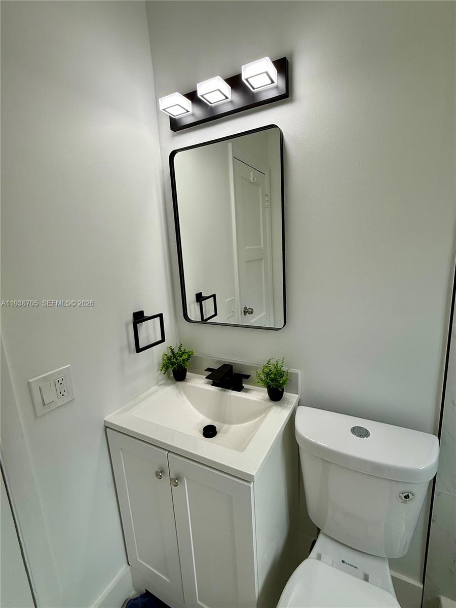 864 80th Street, Unit 1 Miami Beach, FL 33141 - Photo 13 of 13 a bathroom with a toilet sink and mirror