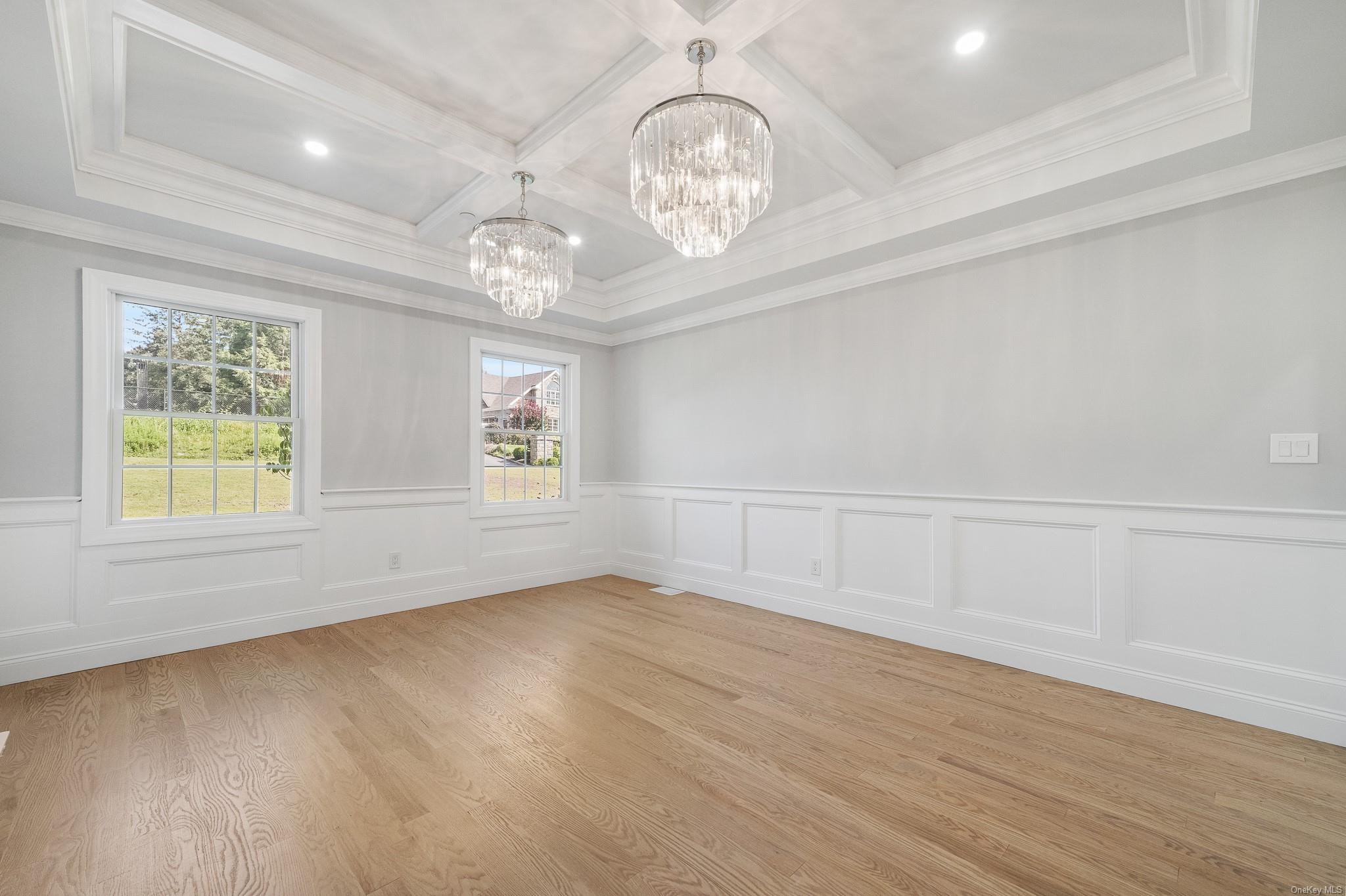 47 Laurel Lane Locust Valley, NY 11560 - Photo 19 of 39 Empty room featuring beamed ceiling, coffered ceiling, an inviting chandelier, and light hardwood / wood-style flooring