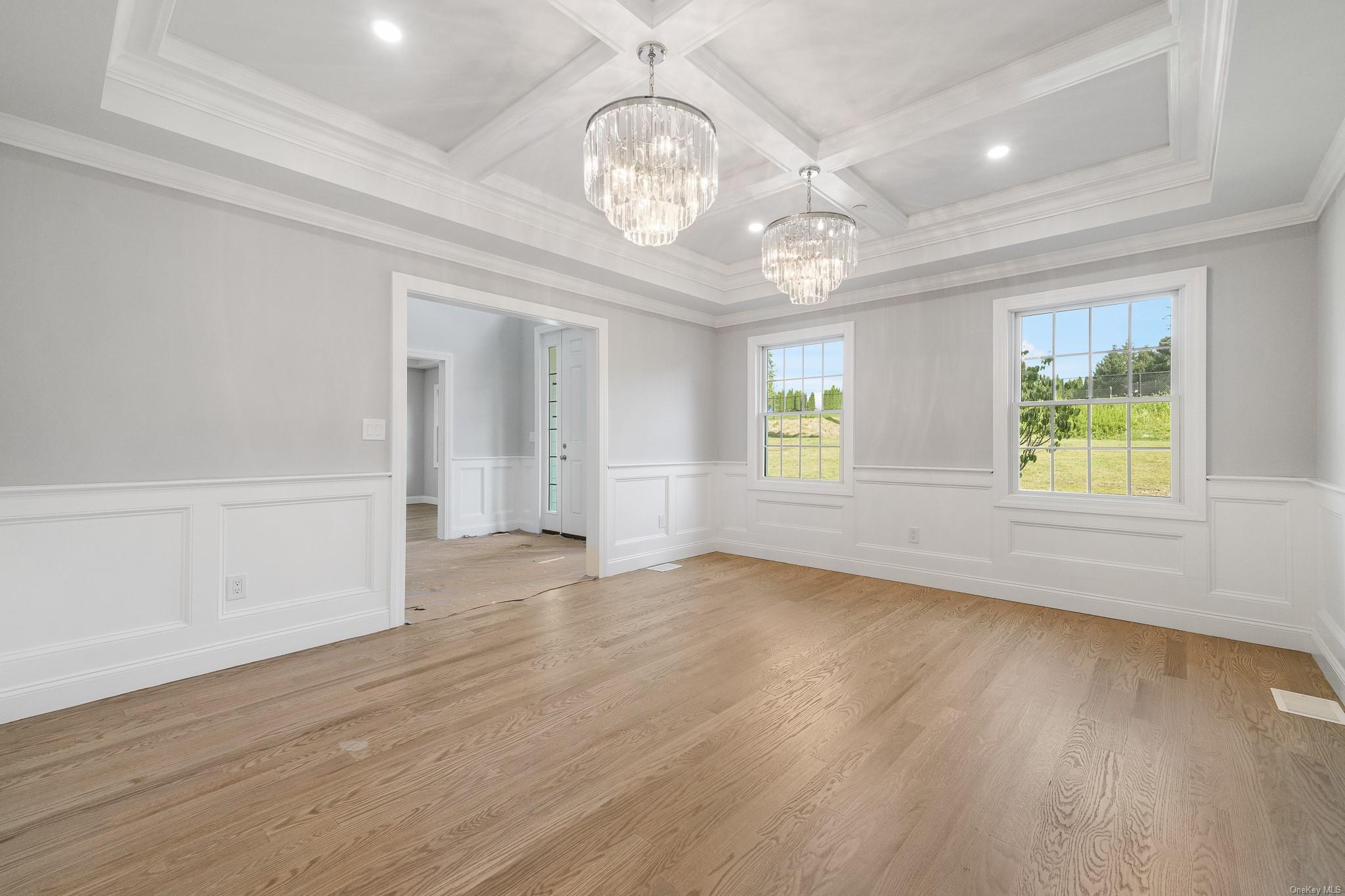 47 Laurel Lane Locust Valley, NY 11560 - Photo 20 of 39 Unfurnished room featuring an inviting chandelier, coffered ceiling, ornamental molding, light hardwood / wood-style floors, and beamed ceiling