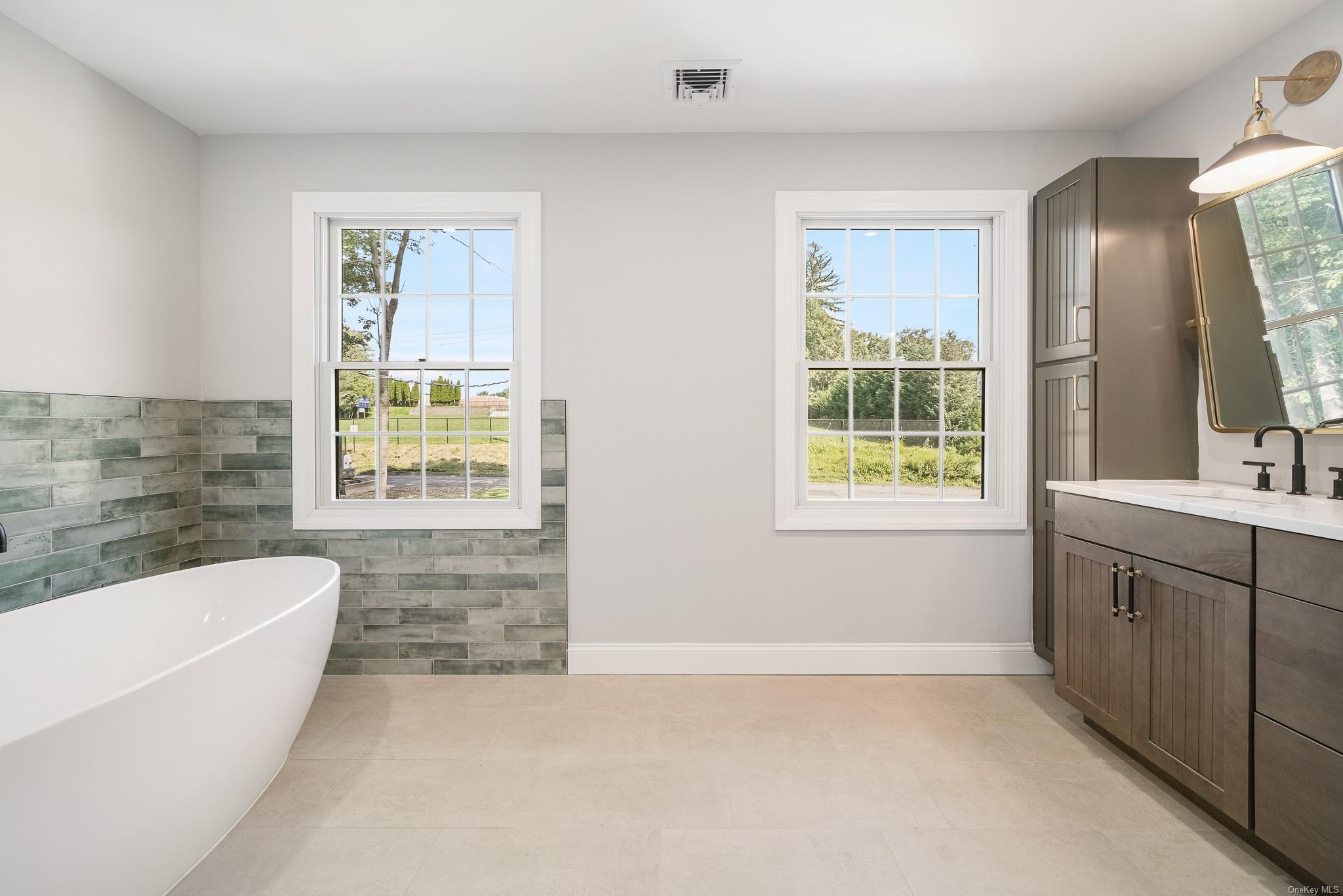 47 Laurel Lane Locust Valley, NY 11560 - Photo 32 of 39 Bathroom featuring a tub to relax in, vanity, tile patterned flooring, and tile walls