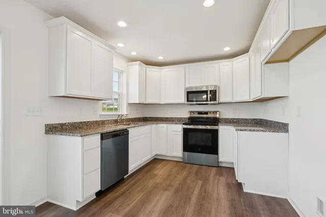 a kitchen with granite countertop white cabinets and black stainless steel appliances