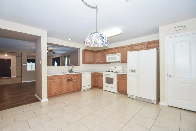 a large white kitchen with a sink and dishwasher a refrigerator with white cabinets