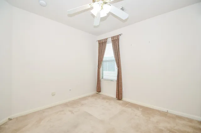 an empty room with a chandelier fan and windows