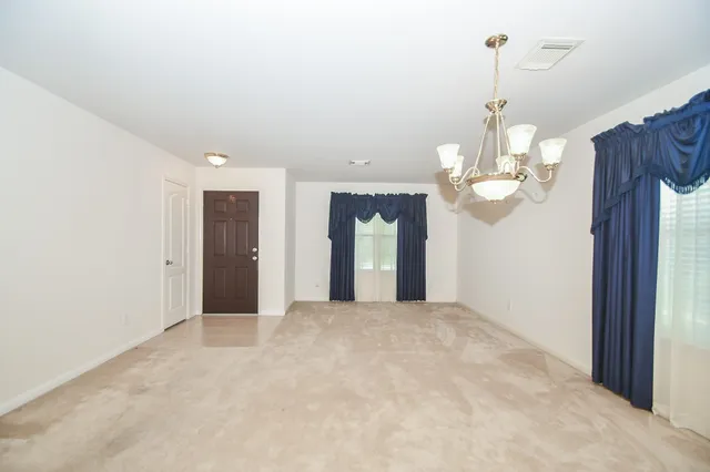 a view of a room with a chandelier fan and kitchen view
