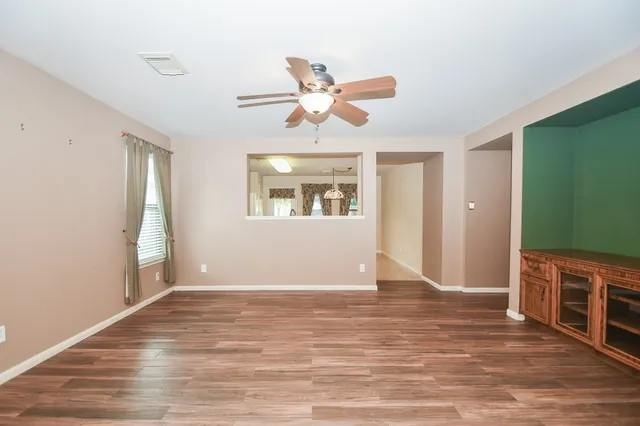 a view of an empty room with window and wooden floor