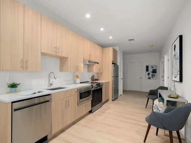 a kitchen with stainless steel appliances granite countertop a sink a stove a refrigerator cabinets and chairs