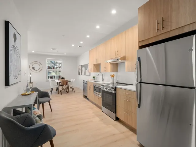 a kitchen with stainless steel appliances granite countertop a refrigerator a stove a sink a dining table and chairs with wooden floor