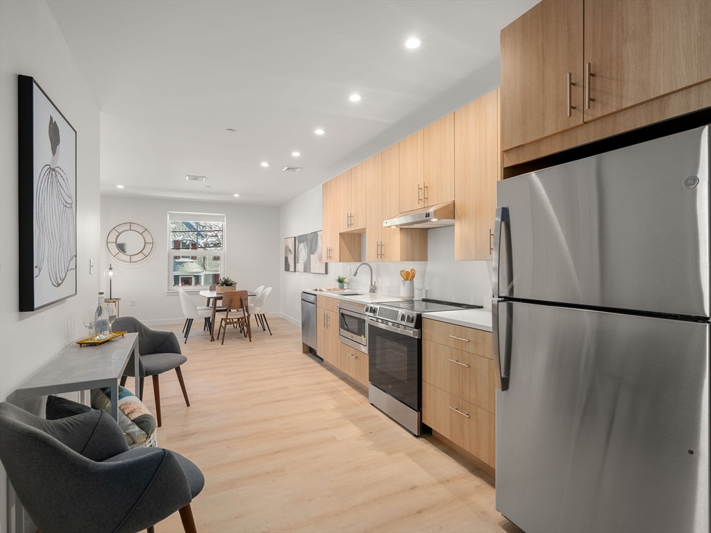 1151 Walnut Street, Unit 201 Newton, MA 02461 - Photo 10 of 31 a kitchen with stainless steel appliances granite countertop a refrigerator a stove a sink a dining table and chairs with wooden floor