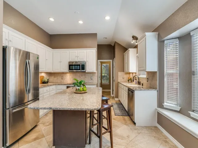 a kitchen with a refrigerator a stove a sink and white cabinets with wooden floor