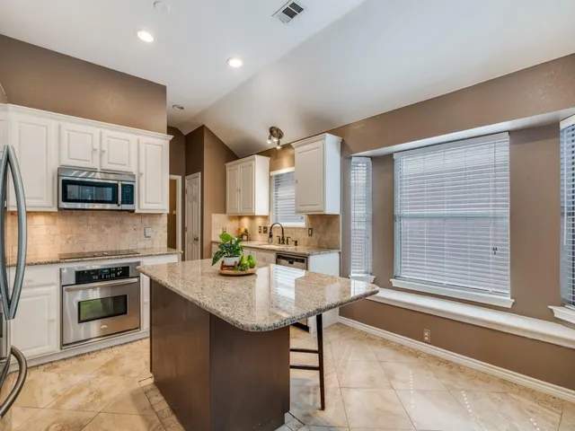a kitchen with kitchen island granite countertop a sink cabinets and stainless steel appliances