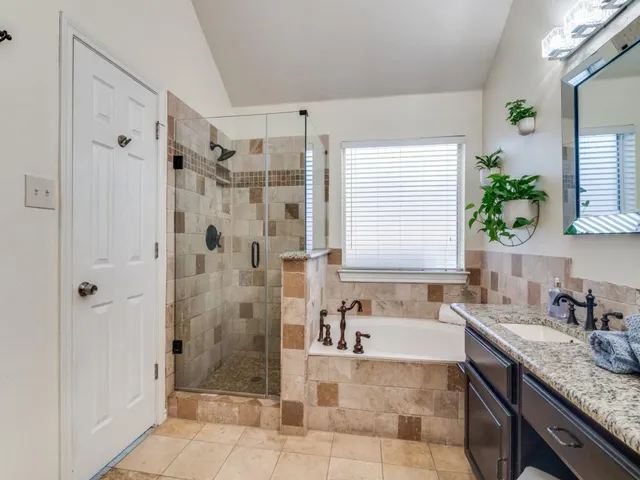 a bathroom with a granite countertop sink a mirror a bathtub and shower