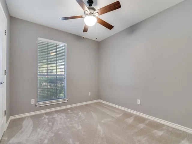 an empty room with a window and a fan