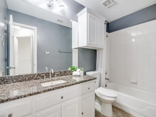 a bathroom with a granite countertop sink a toilet and shower