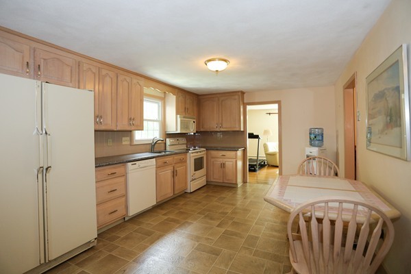 88 Warren Road Sudbury, MA 01776 - Photo 8 of 16 a kitchen with granite countertop a refrigerator a sink dishwasher a stove and white cabinets with wooden floor