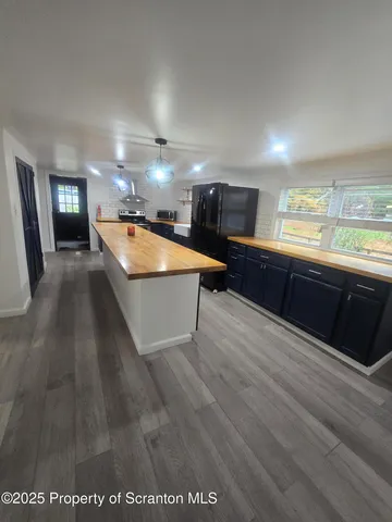 a room with stainless steel appliances kitchen island granite countertop a sink and a black cabinets