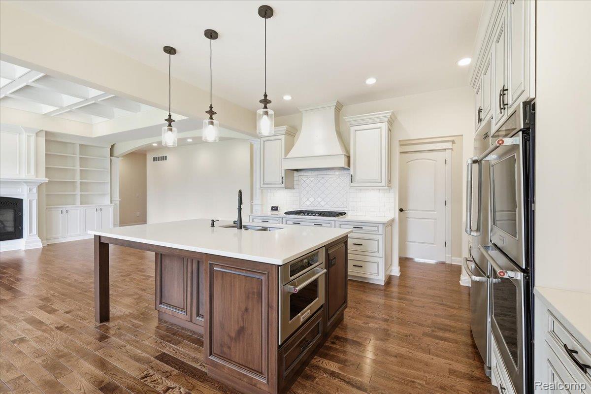 35339 West 13 Mile Road Farmington, MI 48331 - Photo 70 of 72 Kitchen featuring open floor plan, a kitchen island with sink, two tone color scheme, arched walkways, and a glass covered fireplace
