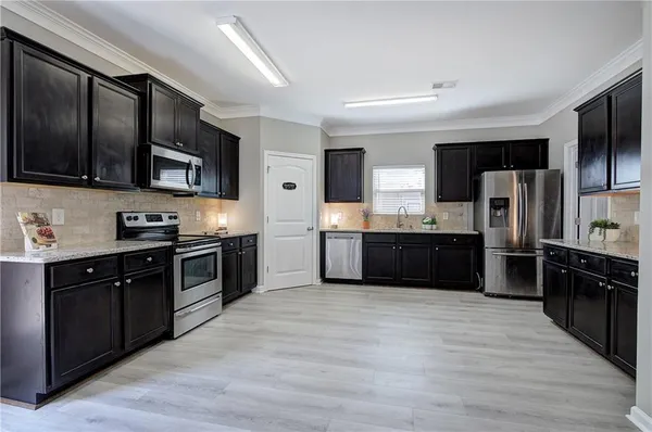 a large kitchen with stainless steel appliances wooden cabinets and a wooden floor