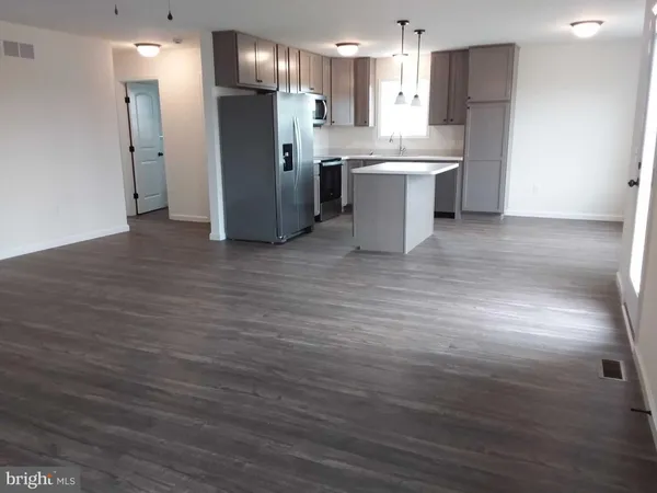 a large kitchen with a wooden floor cabinets a refrigerator and a sink