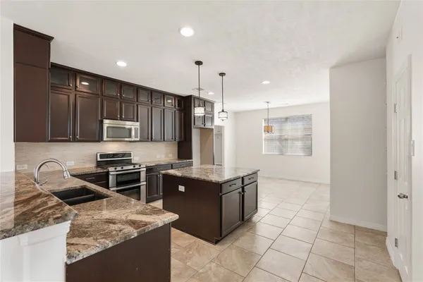 a kitchen with stainless steel appliances kitchen island granite countertop a refrigerator and a sink