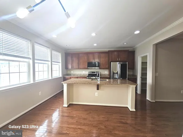 a view of open kitchen with kitchen island a sink wooden floor and a refrigerator