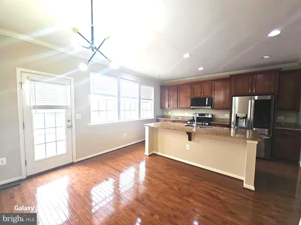 a kitchen with stainless steel appliances granite countertop a refrigerator a sink dishwasher a stove and white cabinets with wooden floor