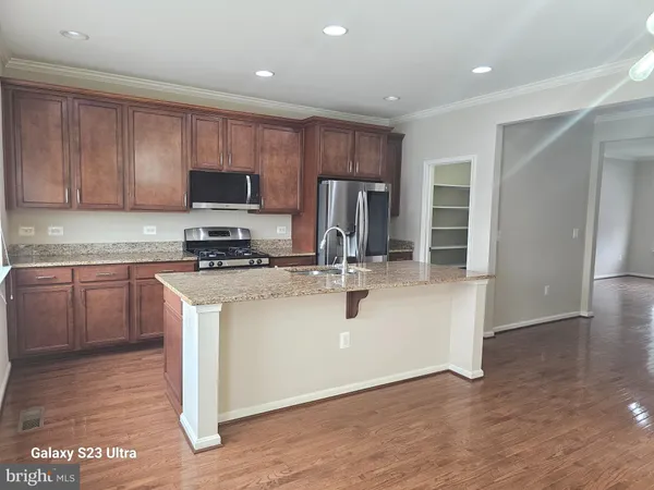 a kitchen with kitchen island granite countertop a sink cabinets and stainless steel appliances
