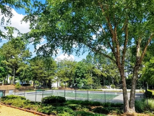 a view of a swimming pool with a patio and trees