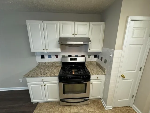 a kitchen with granite countertop white cabinets and black appliances