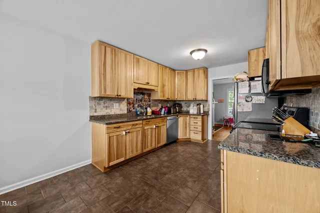 a kitchen with granite countertop a stove a sink a refrigerator and cabinets