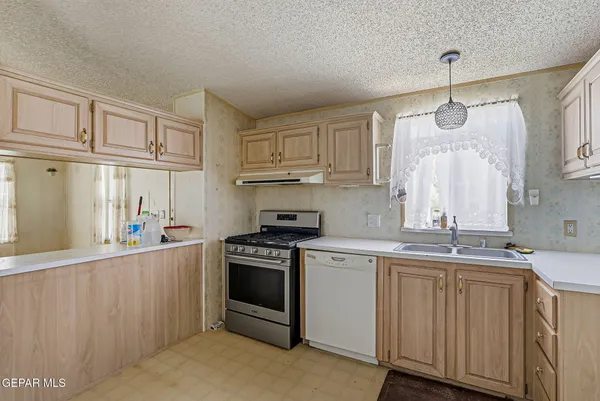 a kitchen that has a sink a stove and cabinets