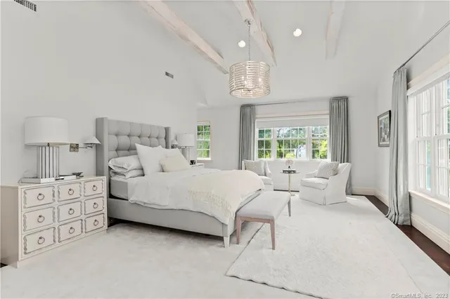 a large white bed sitting in a bedroom next to a window and a larger closet