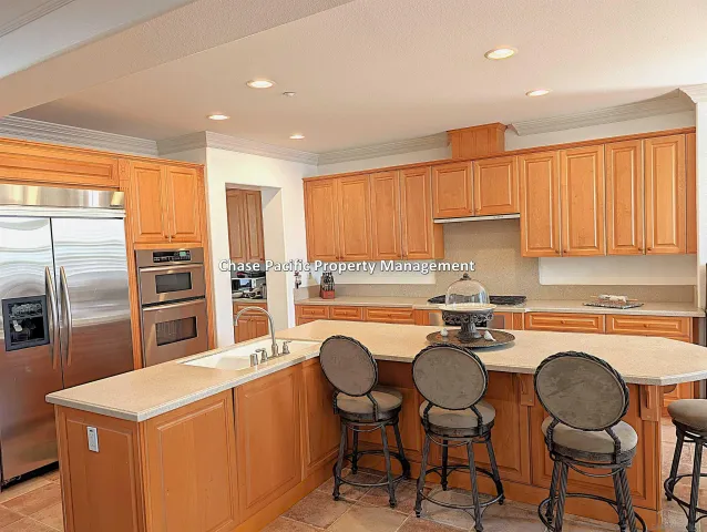 a kitchen with stainless steel appliances a table chairs refrigerator and cabinets