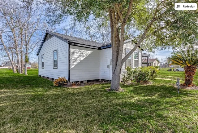 a backyard of a house with plants and large tree