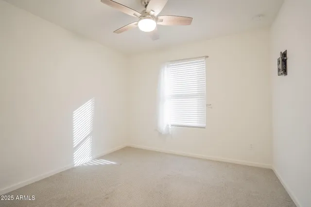 an empty room with a window and ceiling fan