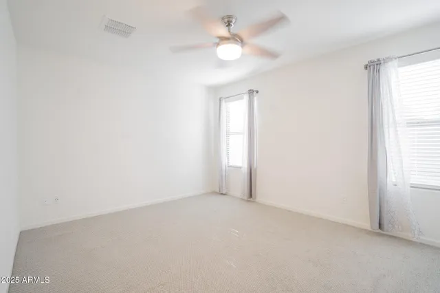 an empty room with a window and a ceiling fan