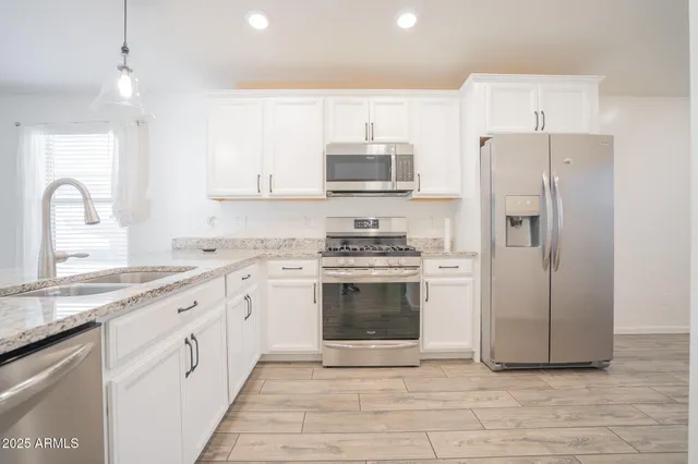 a kitchen with stainless steel appliances granite countertop a refrigerator a sink a stove a microwave and wooden cabinets