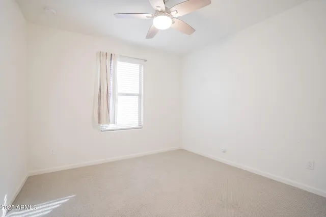 an empty room with a window and a fan
