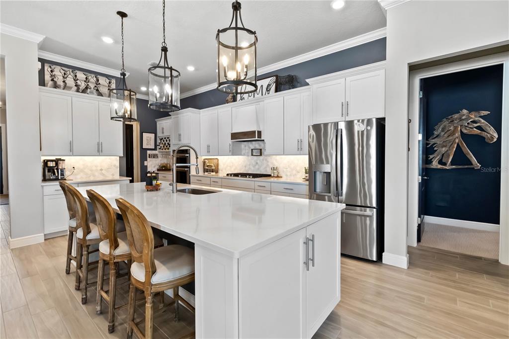 2744 Nature Vw Road St. Cloud, FL 34771 - Photo 3 of 49 a kitchen with stainless steel appliances kitchen island granite countertop a refrigerator a stove a kitchen island with a dining table and wooden floor