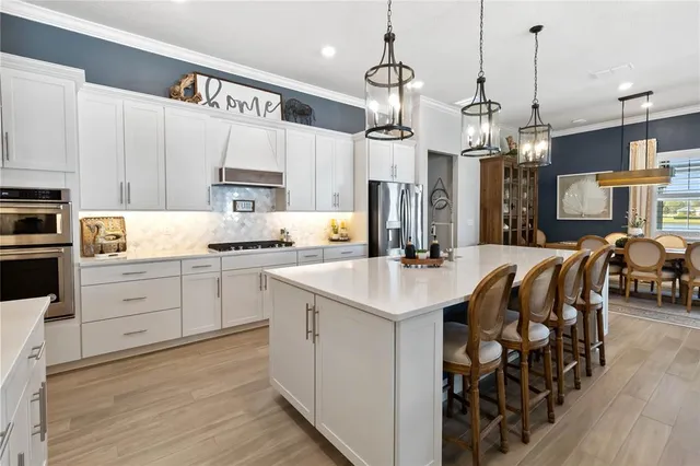 a kitchen with stainless steel appliances kitchen island granite countertop a sink a stove a refrigerator and white cabinets