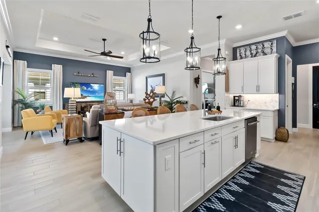 a large white kitchen with a large island oven a stove a sink a dining table and chairs