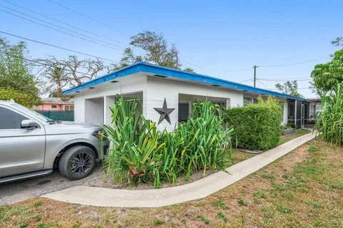 a view of a house with a small yard plants and a large tree